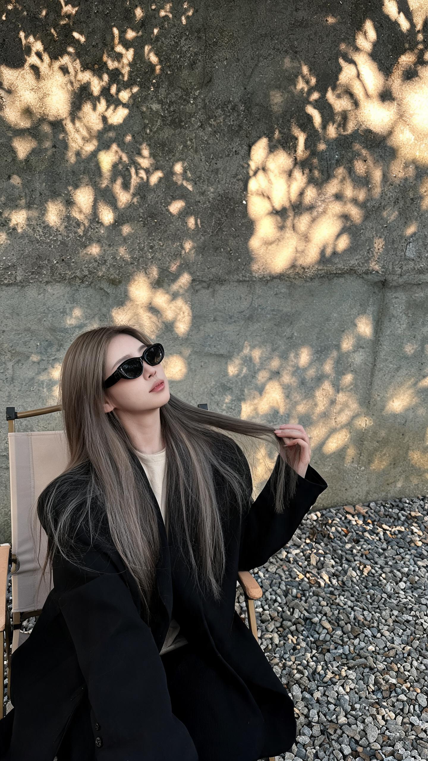 质感对撞法效果图一:水泥墙前穿黑色西装的少女,左手撩发,阳光斑驳,左侧构图右侧留白,冷白皮暖光对比